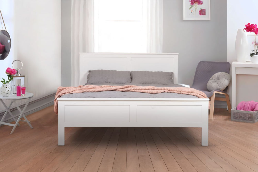 A white, wooden bed frame in a modern room with gray walls and a wooden floor. There are accents of pink in the room.