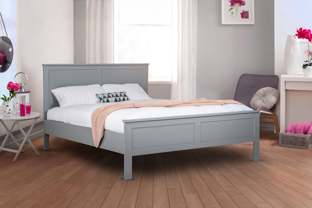 A white, wooden bed frame in a modern room with gray walls and a wooden floor. There are accents of pink in the room.