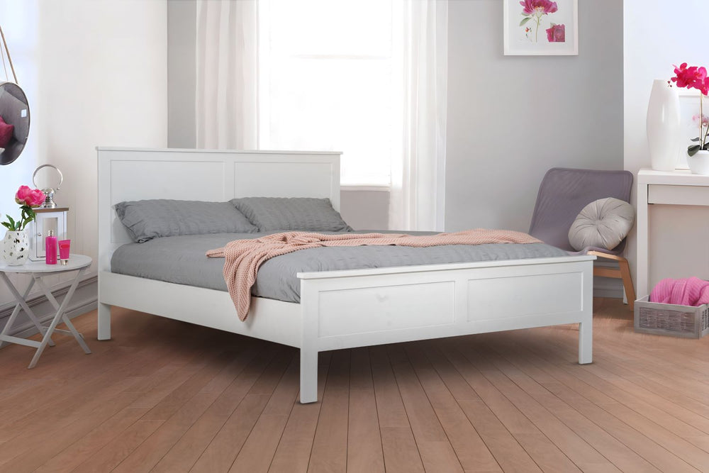 
                  
                    A white, wooden bed frame in a modern room with gray walls and a wooden floor. There are accents of pink in the room.
                  
                