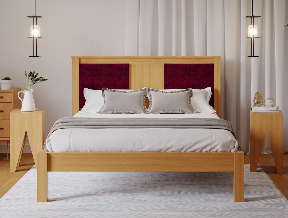 A wooden bed frame with a deep red fabric square either side of the head board. The room has a wooden floor and white walls. 