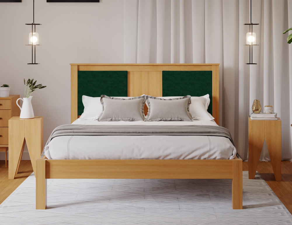 A wooden bed frame with an emerald green fabric square either side of the head board. The room has a wooden floor and white walls. 